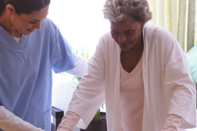 healthcare staff helping senior woman to practice walk